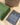 Green bag with 'seekers' branding on a wooden surface with a brown box and black paper.